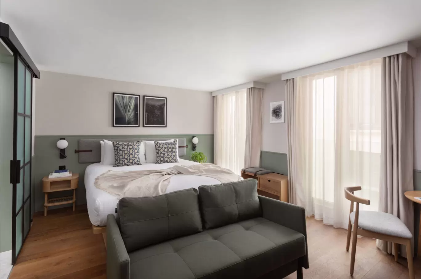 Bedroom at Inhabit hotel with grey sofa at the end of the bed