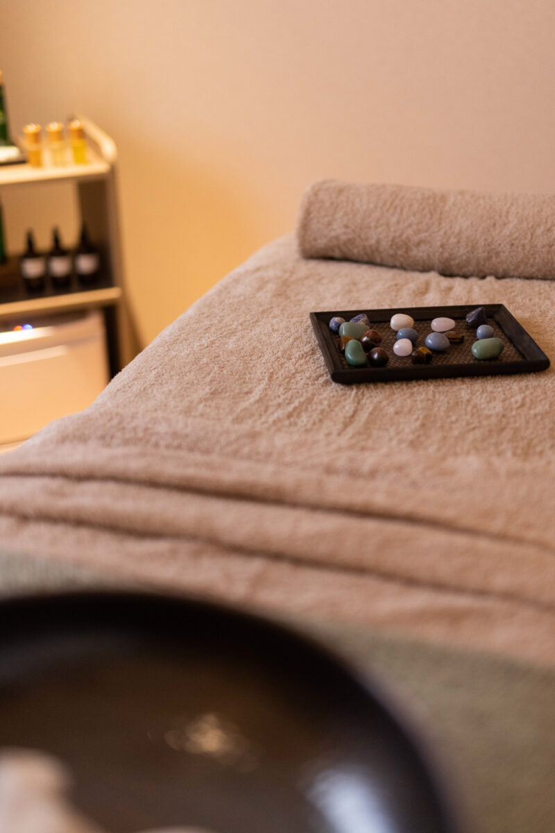 spa room bed with different crystals on a black plate