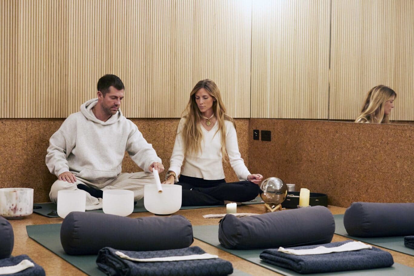 two people working with sound bowls with yoga mats in front of them