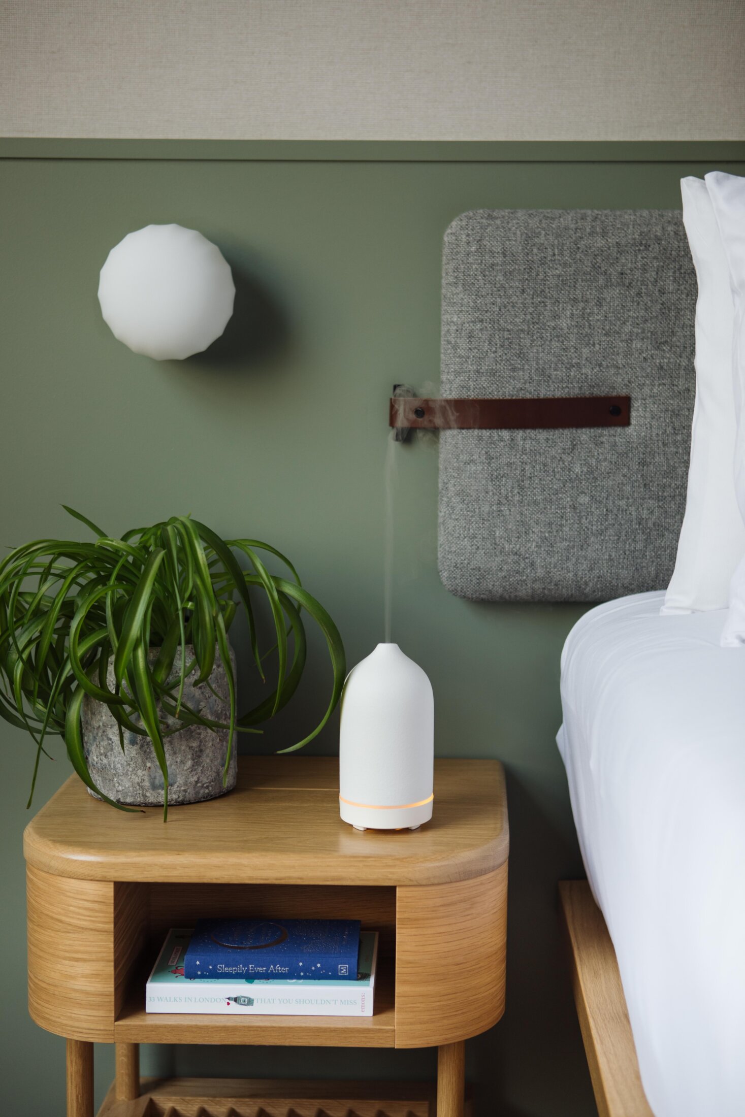 Aromatherapy essential oil electronic diffuser on a bedside table of a modern hotel room at Inhabit Hotels